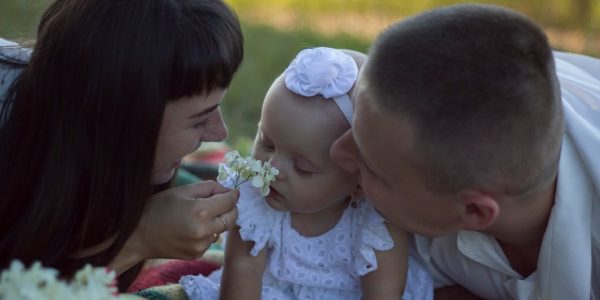 A loving family moment with parents and baby at a sunny outdoor picnic.